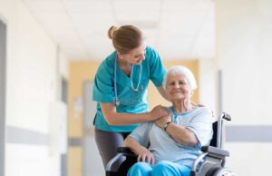 A senior talking with a caregiver in a comfortable, sunlit room with medical and personal care items nearby.