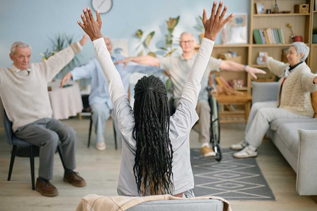 An older adult smiling and unpacking boxes with the help of a supportive family member in a bright, home-like room.